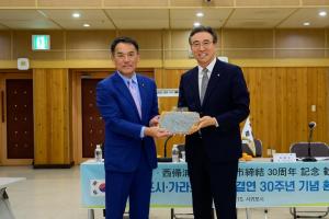 西帰浦市長から唐津市長に記念品の済州島の形をした皿が贈呈される様子