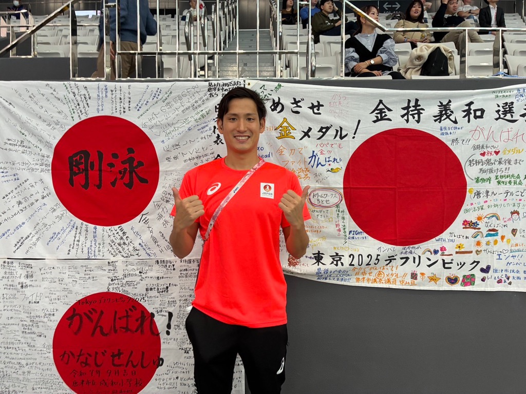 寄書きの前でポーズをとる金持選手