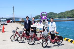 海をバックに市長、代表取締役、徳川慎之介選手、唐ワンくんで撮影した写真